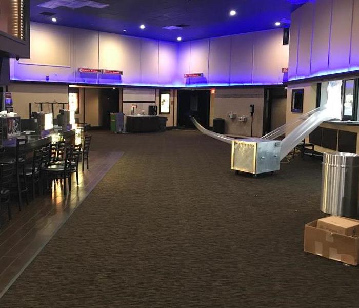lobby of a movie theater with water damage on the floor and a drying equipment set up for mitigation process.