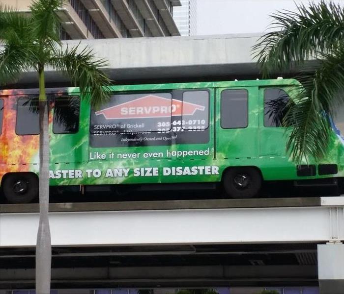 Metro mover car with SERVPRO of Brickell Wrap tall building in background flanked by palm trees
